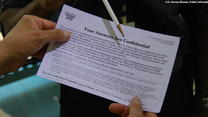 Close-up of a 2010 Census interviewer reviews a confidentiality notice with a household resident.