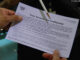 Close-up of a 2010 Census interviewer reviews a confidentiality notice with a household resident.