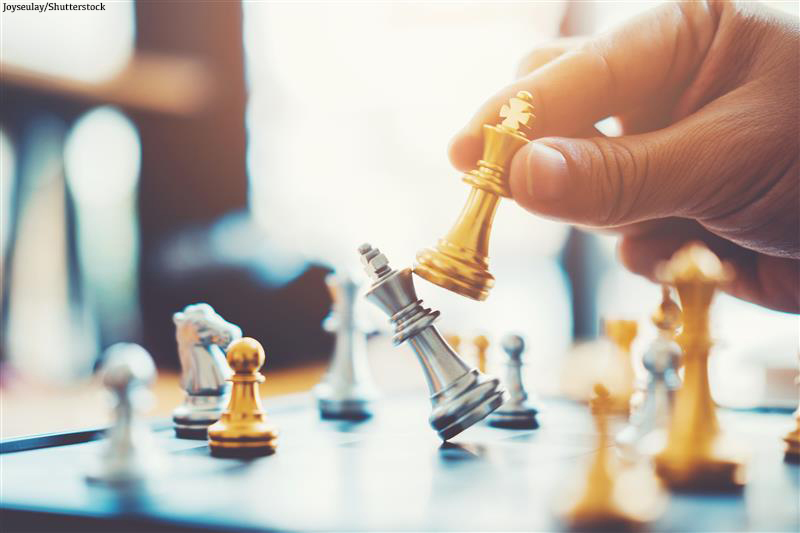 close up of someone moving chess pieces on a chess board