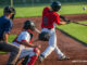 Batter, catcher, and umpire at home plate on a baseball field.