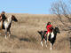 Two Native American Indians riding horseback through the prairie of South Dakota.