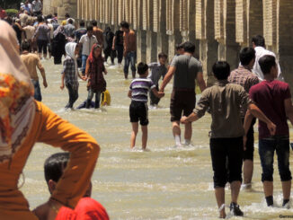Crowd of people wading in the Zayandeh River as it passes under the Si-o-seh pol or Allāhverdi Khan Bridge in Isfahan, Iran.