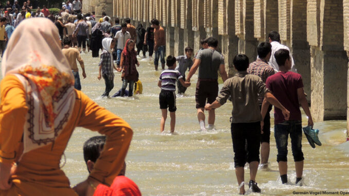 Crowd of people wading in the Zayandeh River as it passes under the Si-o-seh pol or Allāhverdi Khan Bridge in Isfahan, Iran.
