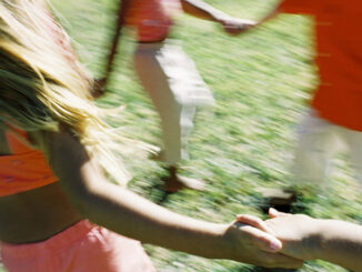 blurred image of children dancing in a circle