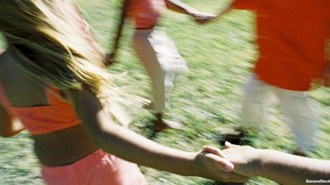 blurred image of children dancing in a circle